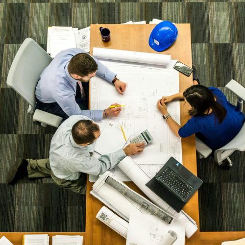 pexels-photo-416405-416405 Top view of a team working on construction plans in an office setting.
